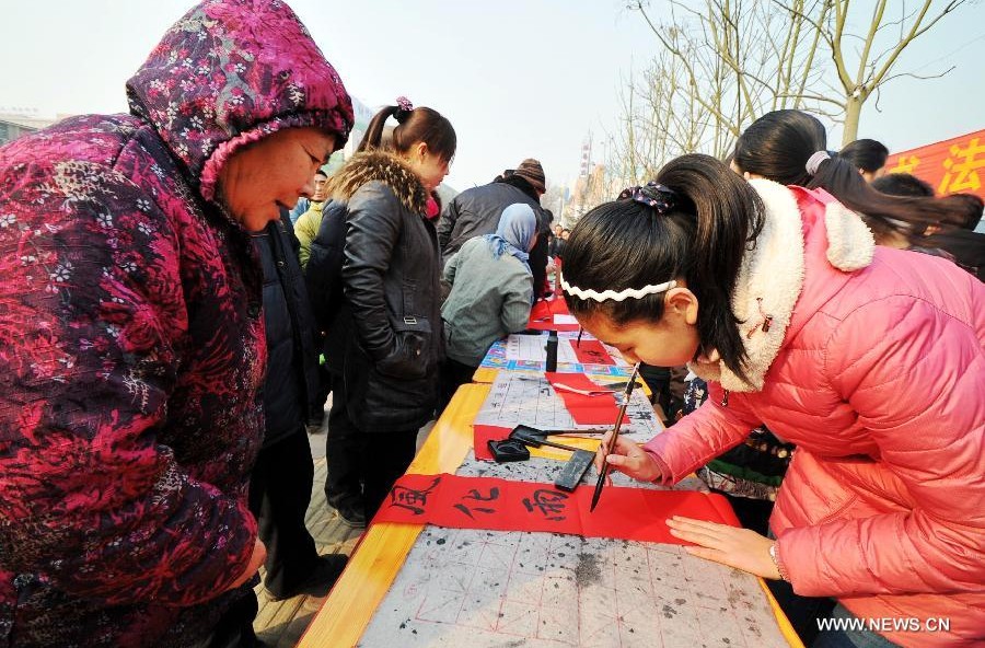 Students of calligraphy school write Spring Festival couplets for residents